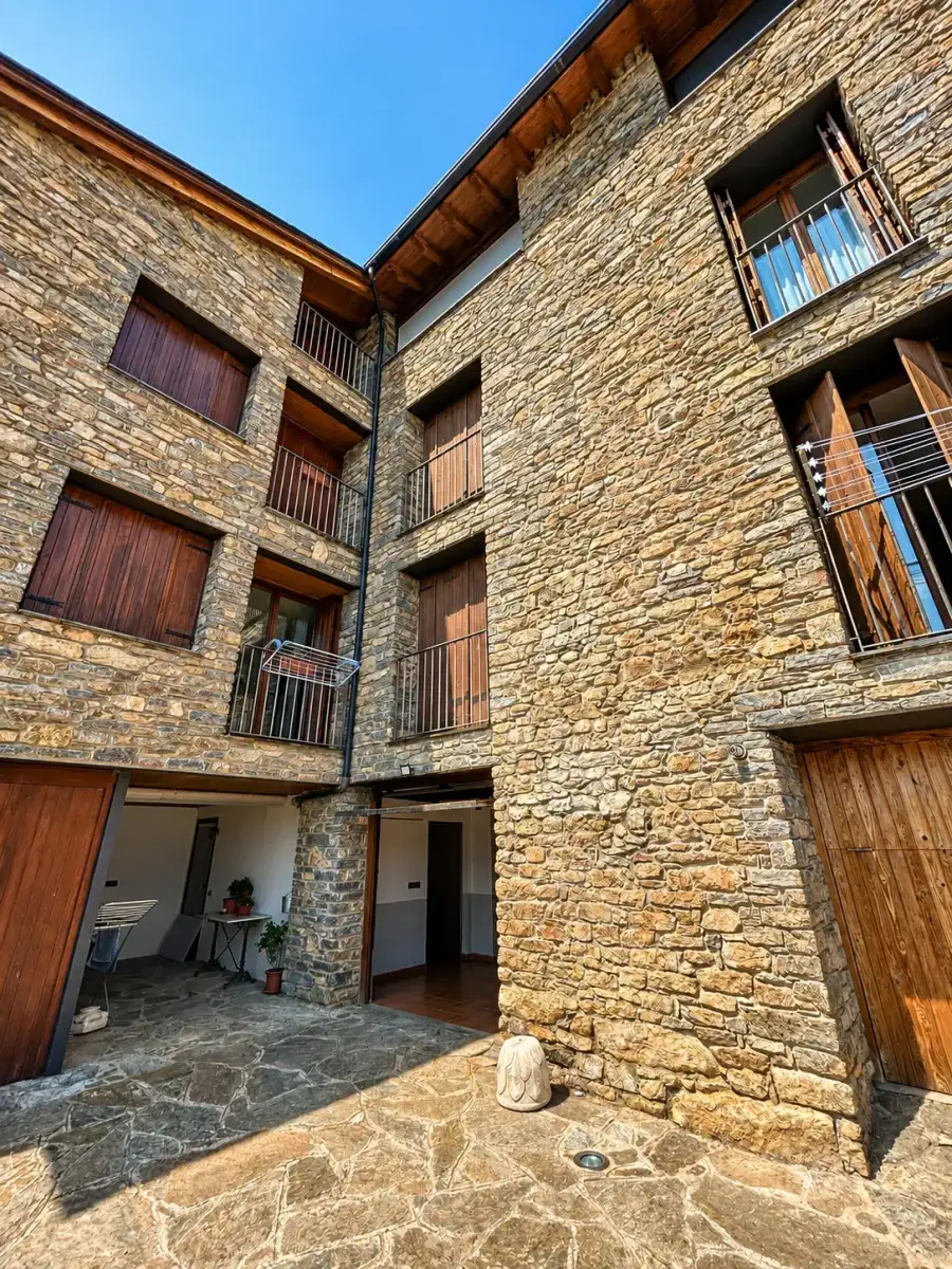 Façana de pedra de Casa Jonico des del pati, amb els seus pisos